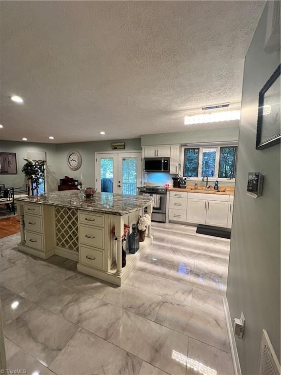 bathroom featuring a sink, a textured ceiling, baseboards, recessed lighting, and marble finish floor