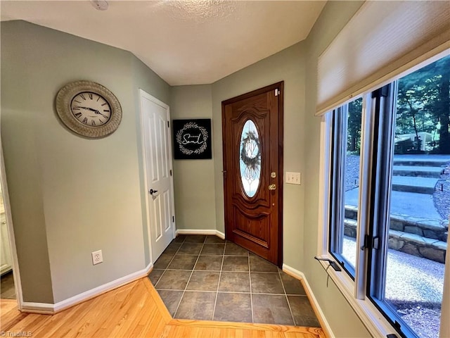 foyer with baseboards and dark tile patterned floors