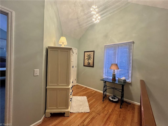 interior space featuring vaulted ceiling, a notable chandelier, light wood finished floors, and baseboards