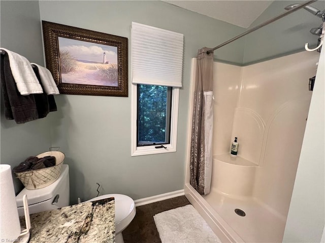 bathroom with baseboards, toilet, and a stall shower