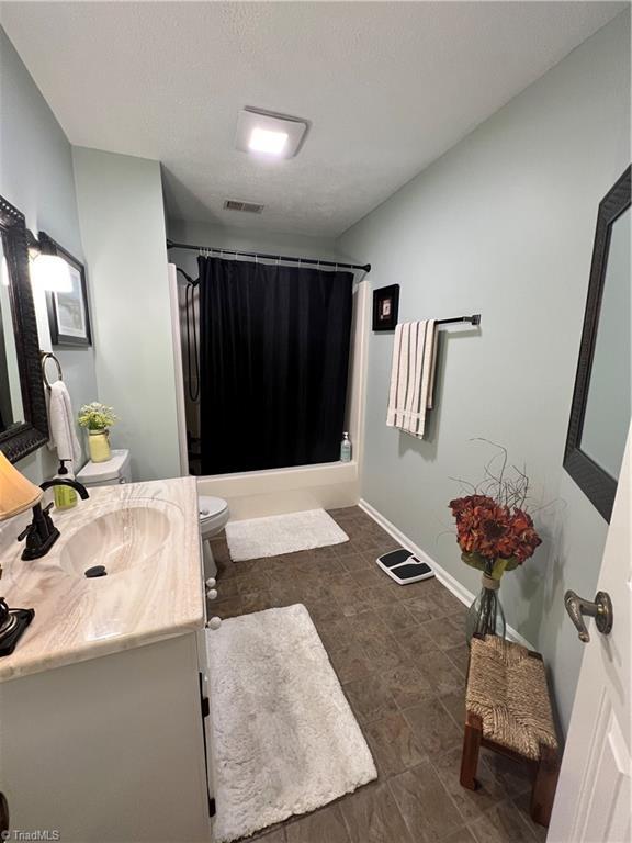 full bath with vanity, shower / tub combo with curtain, baseboards, toilet, and visible vents