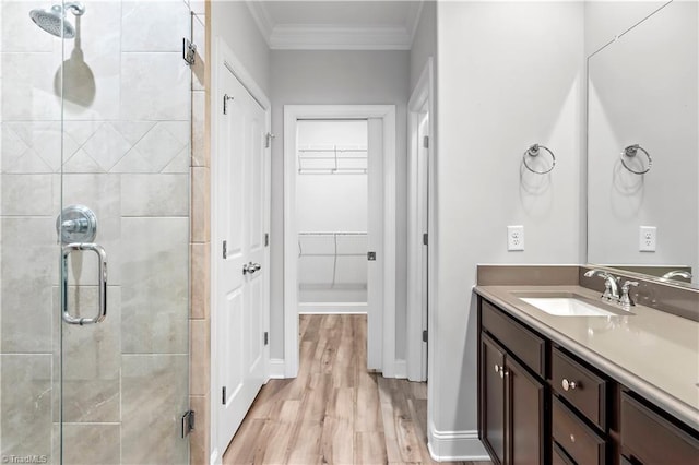 bathroom with vanity, a shower with door, ornamental molding, and hardwood / wood-style floors