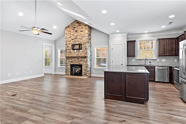 kitchen featuring appliances with stainless steel finishes, a kitchen island, a fireplace, a wealth of natural light, and sink