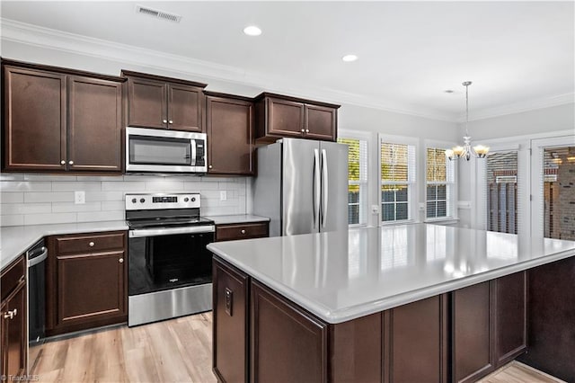 kitchen featuring decorative light fixtures, stainless steel appliances, an inviting chandelier, tasteful backsplash, and crown molding