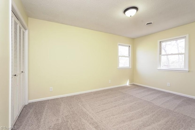 unfurnished bedroom featuring light colored carpet, a closet, and a textured ceiling