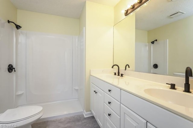 bathroom featuring a shower, a textured ceiling, and toilet