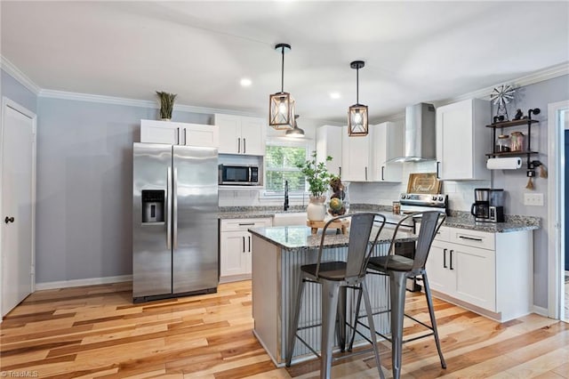 5215 Hicone Rd, Mcleansville, NC 27301 - kitchen featuring appliances with stainless steel finishes, wall chimney range hood, light wood-style flooring, white cabinets, and crown molding