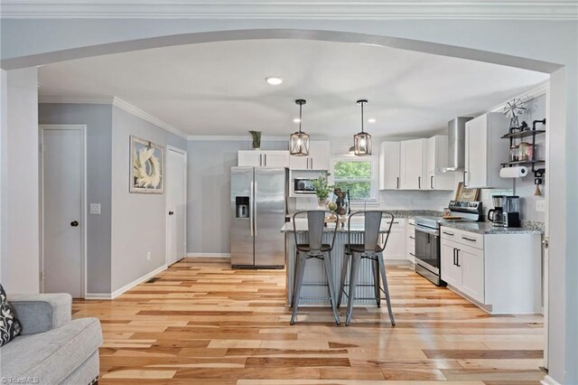 5215 Hicone Rd, Mcleansville, NC 27301 - kitchen with appliances with stainless steel finishes, wall chimney exhaust hood, a kitchen bar, light wood finished floors, and white cabinets
