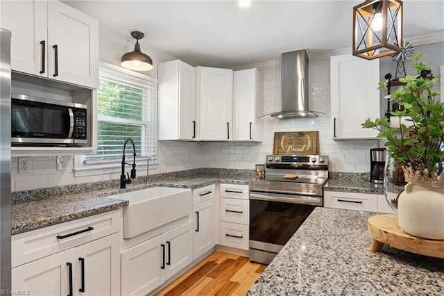 5215 Hicone Rd, Mcleansville, NC 27301 - kitchen with wall chimney range hood, appliances with stainless steel finishes, a sink, white cabinets, and light wood-style floors