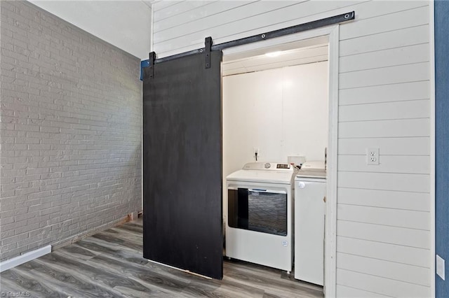 5215 Hicone Rd, Mcleansville, NC 27301 - washroom with washing machine and clothes dryer, brick wall, wood finished floors, and a barn door