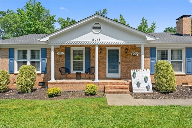 5215 Hicone Rd, Mcleansville, NC 27301 - view of front facade with a porch, brick siding, a chimney, a front lawn, and crawl space