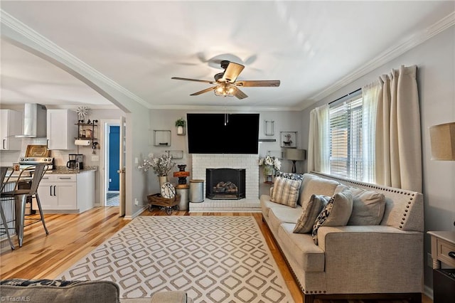 5215 Hicone Rd, Mcleansville, NC 27301 - living room with ceiling fan, light wood finished floors, crown molding, arched walkways, and a brick fireplace