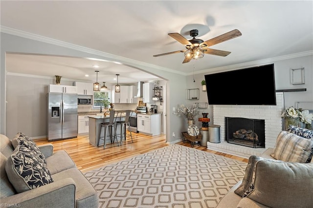 5215 Hicone Rd, Mcleansville, NC 27301 - living room with light wood finished floors, ceiling fan, crown molding, a brick fireplace, and baseboards