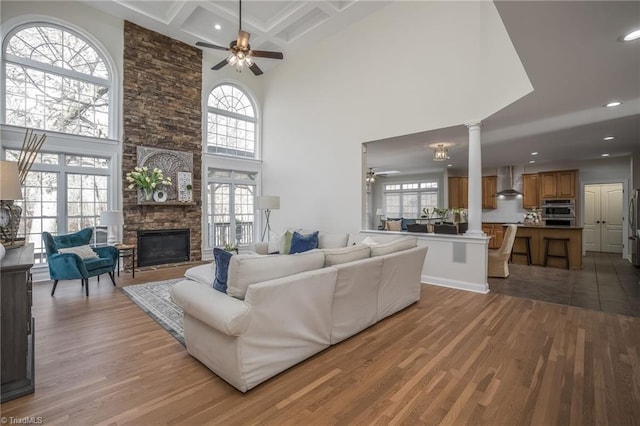 living room with light wood-type flooring, a fireplace, coffered ceiling, and plenty of natural light