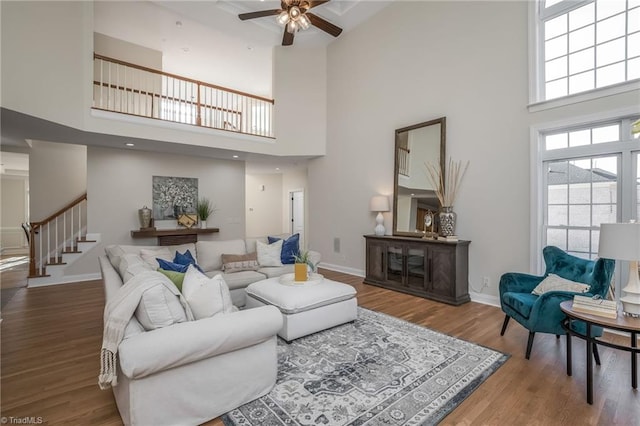 living room featuring a towering ceiling, wood-type flooring, and ceiling fan