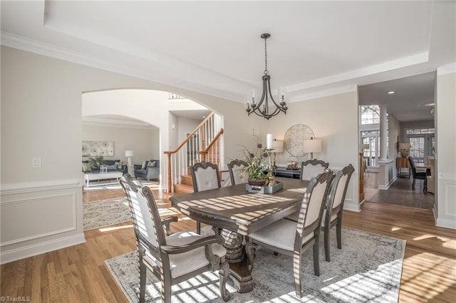 dining space featuring an inviting chandelier, a tray ceiling, hardwood / wood-style floors, and crown molding