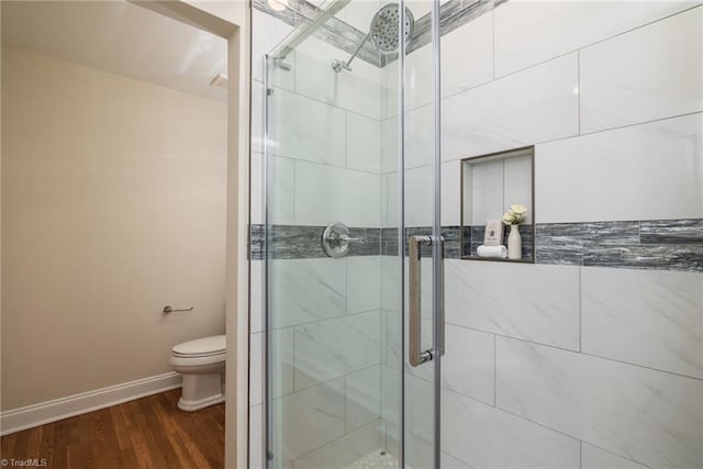 bathroom featuring wood-type flooring, walk in shower, and toilet