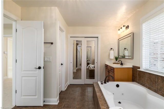 bathroom featuring tile patterned flooring, vanity, and a relaxing tiled tub