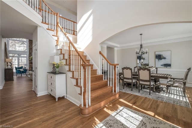 staircase featuring wood-type flooring, a high ceiling, and a notable chandelier