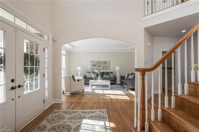 foyer entrance with crown molding, a towering ceiling, and hardwood / wood-style flooring