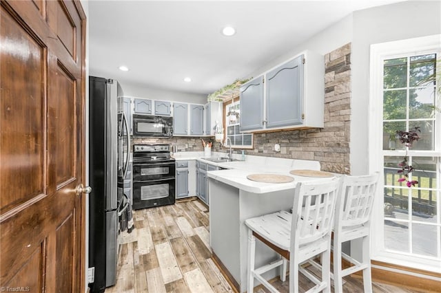 1705 Braemore Ct, Kernersville, NC 27284 - kitchen with gray cabinets, a sink, black appliances, a peninsula, and a breakfast bar