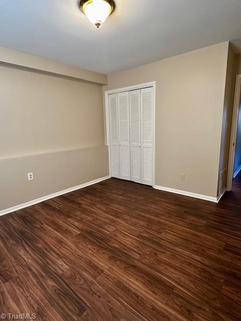 unfurnished bedroom featuring dark hardwood / wood-style floors and a closet