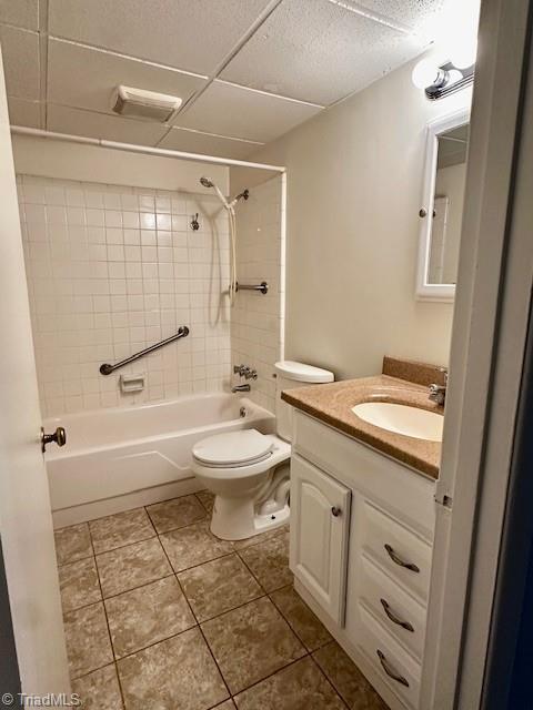 full bathroom with toilet, tiled shower / bath, vanity, tile patterned flooring, and a drop ceiling