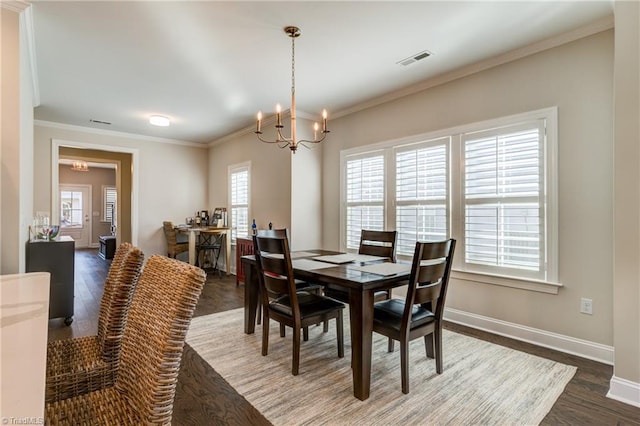 dining space with an inviting chandelier, ornamental molding, and dark hardwood / wood-style flooring