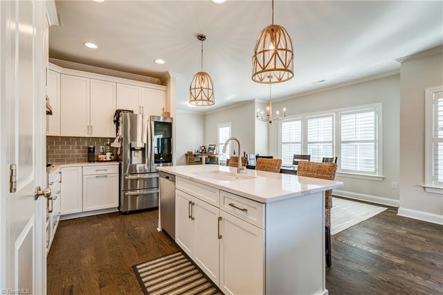 kitchen featuring appliances with stainless steel finishes, pendant lighting, white cabinetry, sink, and a center island with sink