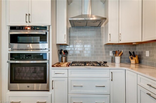 kitchen featuring white cabinetry, appliances with stainless steel finishes, and wall chimney exhaust hood