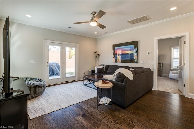 living room with dark wood-type flooring, ornamental molding, and ceiling fan