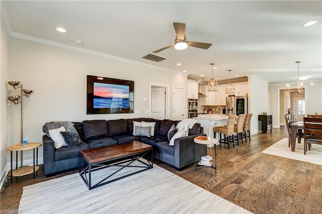 living room featuring sink, crown molding, ceiling fan with notable chandelier, and dark hardwood / wood-style floors