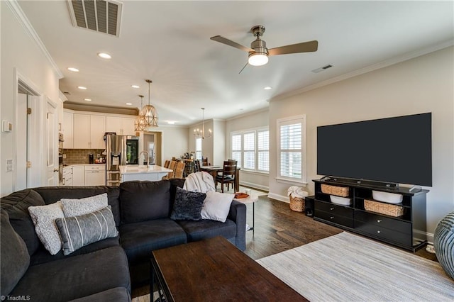 living room featuring ornamental molding, dark hardwood / wood-style flooring, and ceiling fan with notable chandelier