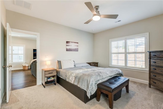 carpeted bedroom featuring multiple windows and ceiling fan