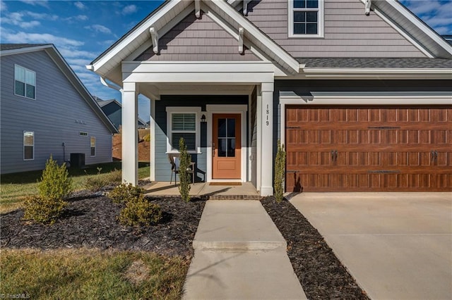 view of front of property featuring a garage, covered porch, and central air condition unit