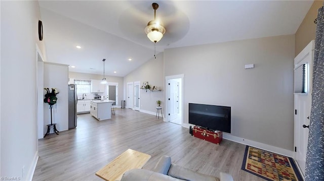 living room featuring ceiling fan, light hardwood / wood-style floors, and lofted ceiling