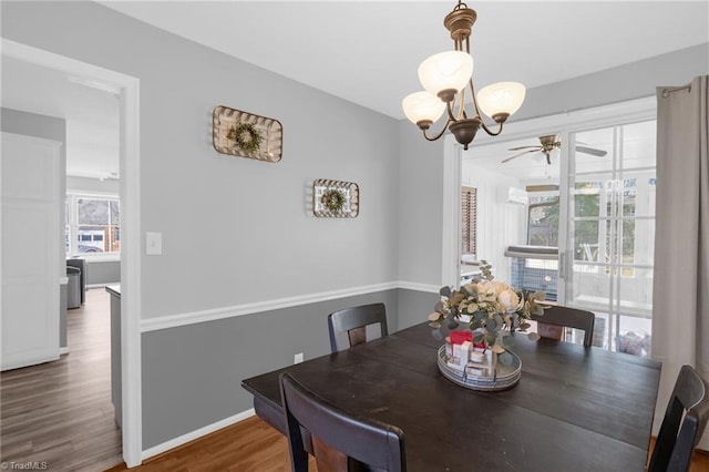 dining area featuring baseboards, dark wood-style flooring, and ceiling fan with notable chandelier