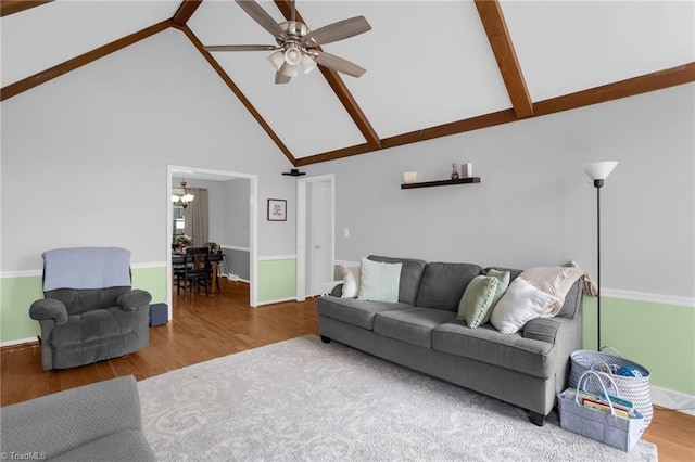 living room with ceiling fan with notable chandelier, high vaulted ceiling, beamed ceiling, and wood finished floors