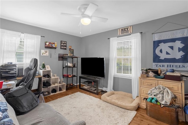 living area with wood finished floors, a ceiling fan, and baseboards