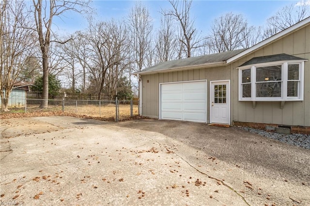 garage featuring concrete driveway and fence