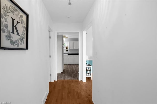 corridor featuring baseboards and wood finished floors