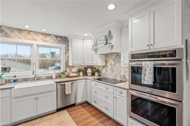 kitchen with white cabinets, sink, light wood-type flooring, and stainless steel appliances