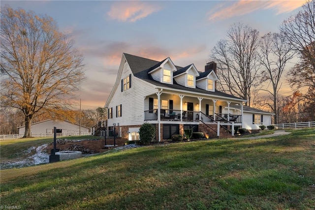 cape cod-style house featuring a yard and a porch