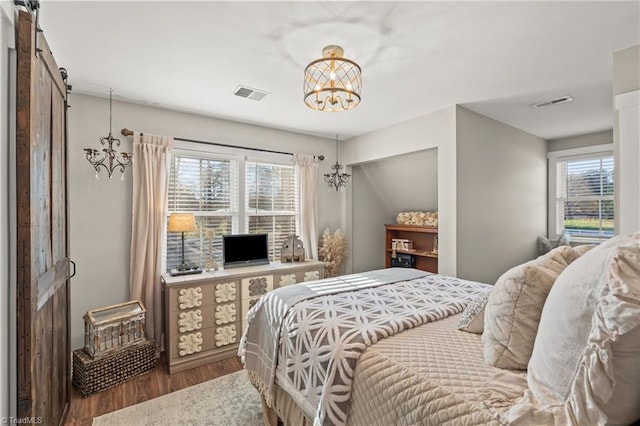 bedroom featuring hardwood / wood-style flooring, a notable chandelier, a barn door, and lofted ceiling