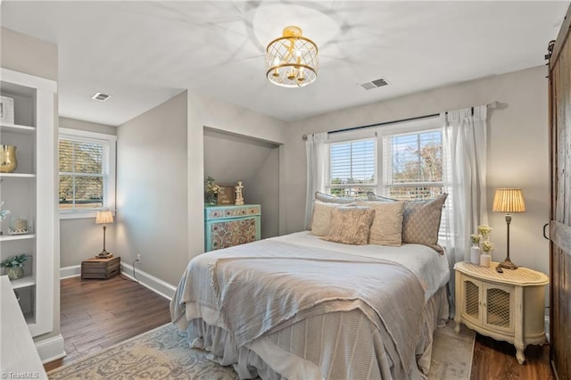 bedroom with multiple windows, an inviting chandelier, and hardwood / wood-style flooring