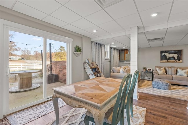 dining space with a paneled ceiling and wood-type flooring