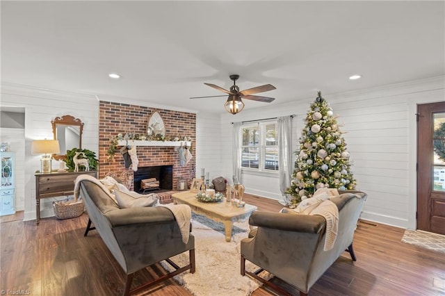 living room featuring ceiling fan, a fireplace, and wood-type flooring