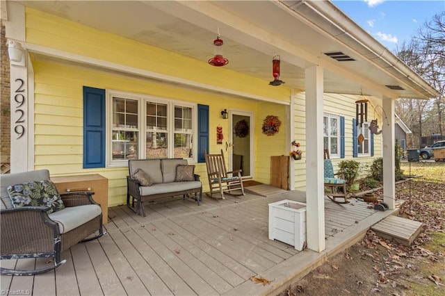 wooden terrace featuring covered porch and an outdoor hangout area