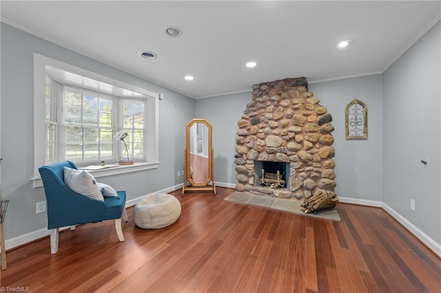 living area featuring crown molding, baseboards, a stone fireplace, and wood finished floors