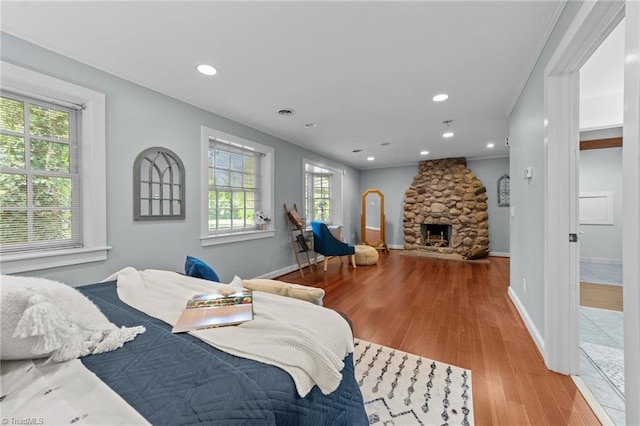 bedroom with recessed lighting, baseboards, wood finished floors, and a fireplace